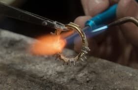 Artisan soldering a ring with a torch