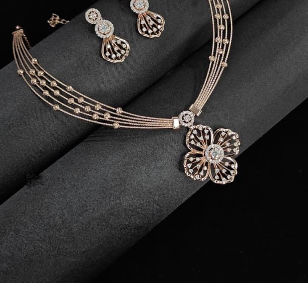 Diamond-set necklace and earrings on dark fabric